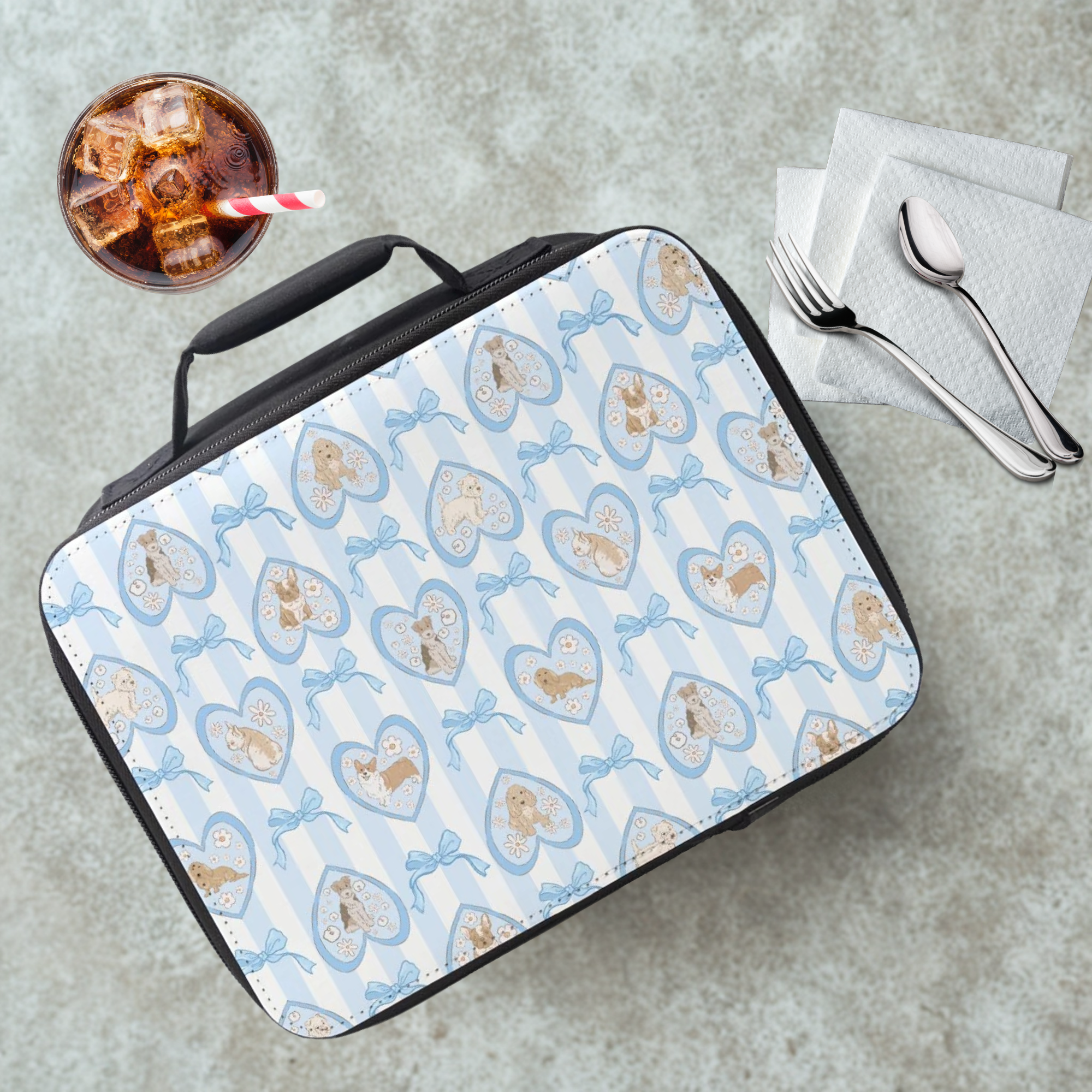 Lunch bag with heart and dog pattern on a cafeteria table with a drink and utensils.