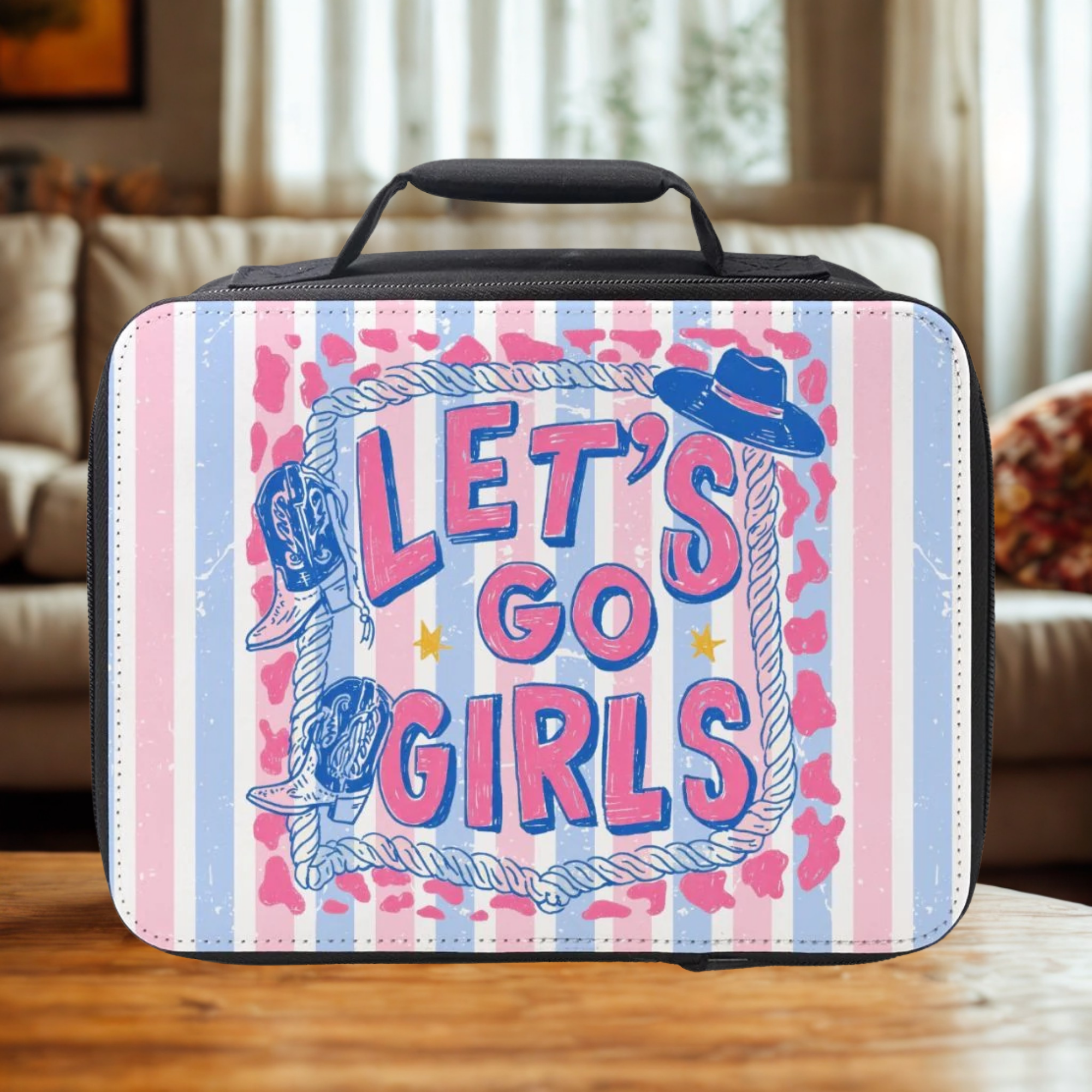 Lunch bag with 'Let's Go Girls' text and cowboy hats on a wooden living room table.