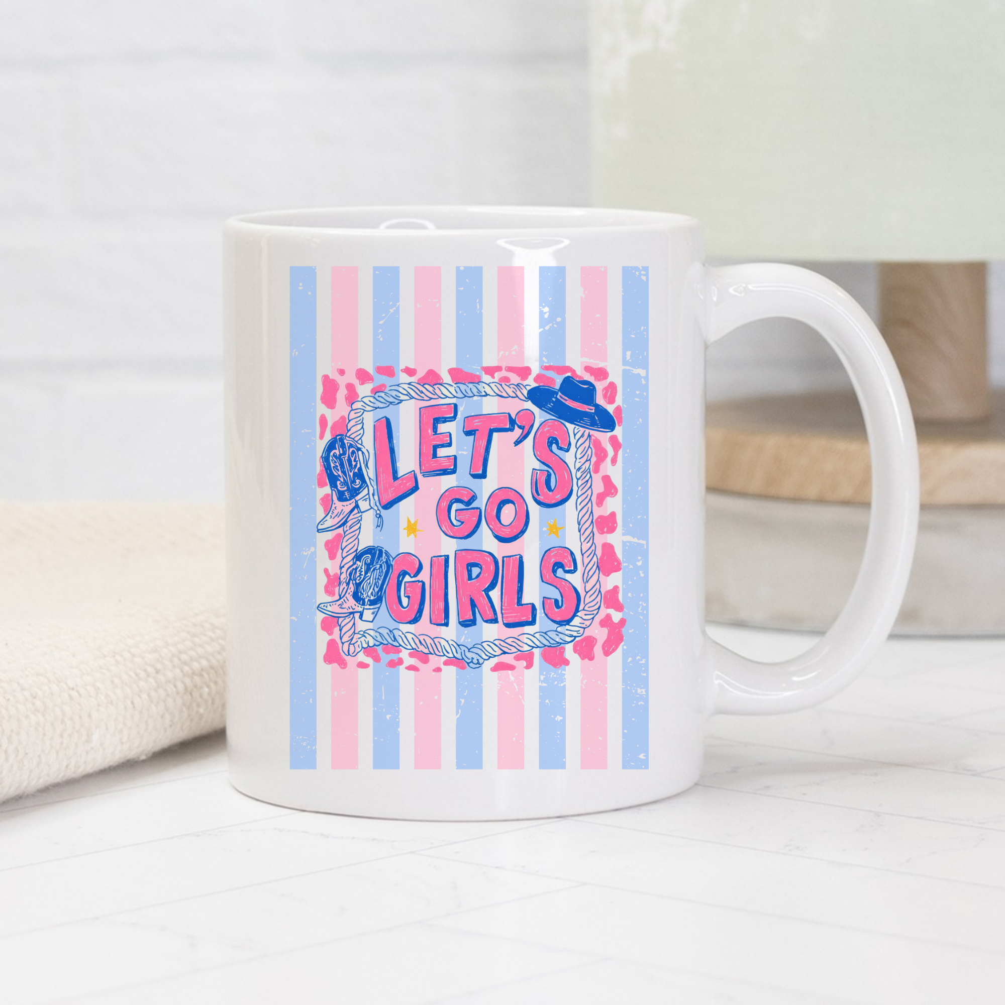 White 11oz. mug with 'Let's Go Girls' design featuring a cowboy hat and lasso on a striped background.