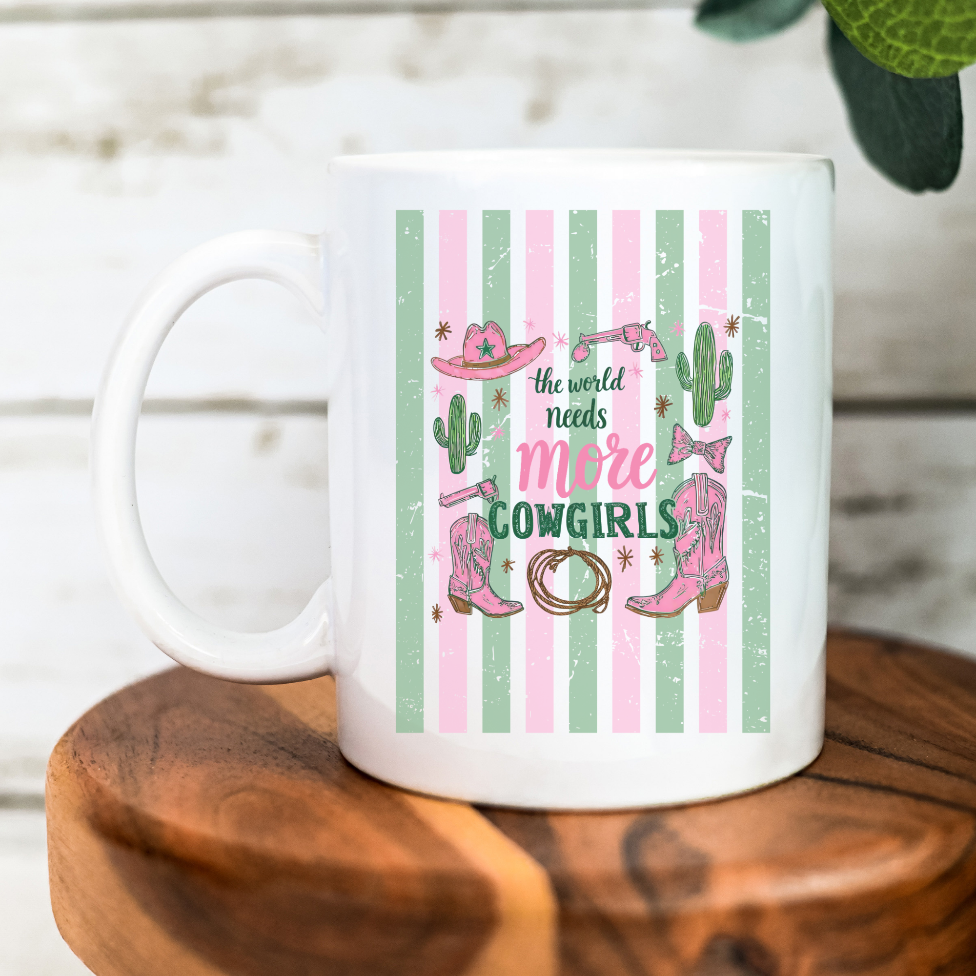 White 11oz mug with pink cowboy boots, cactus, and text on a wooden surface