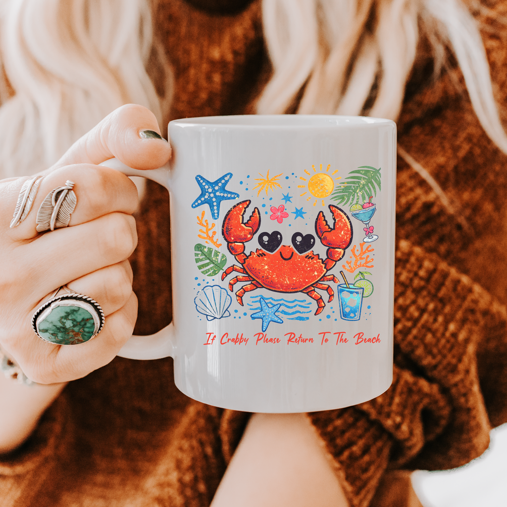Person holding an 11oz. mug with a colorful crab design and text, wearing a brown sweater.