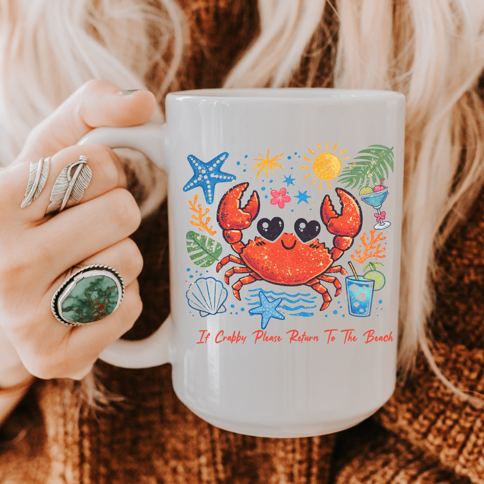 White 11oz. mug with a colorful crab design held by a person wearing rings.