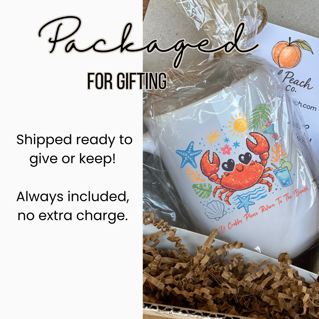 White 15oz. mug with a colorful crab design, wrapped in clear plastic, tied with with twine, inside a white gift box and brown tissue paper, on a white background.