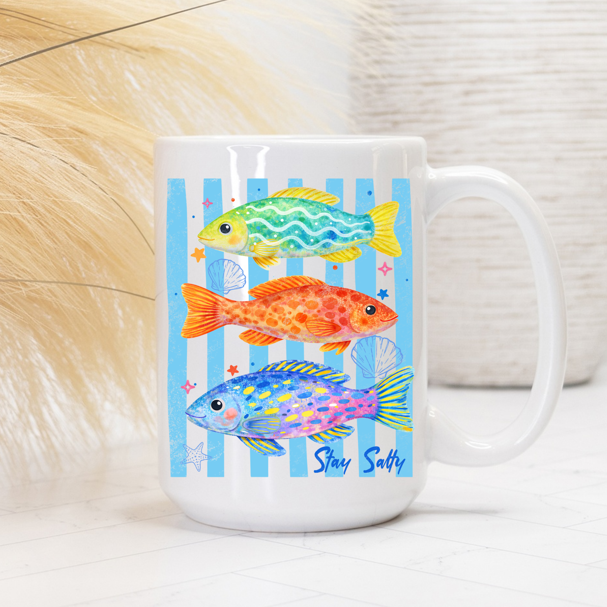White mug with colorful fish design on a blue striped background