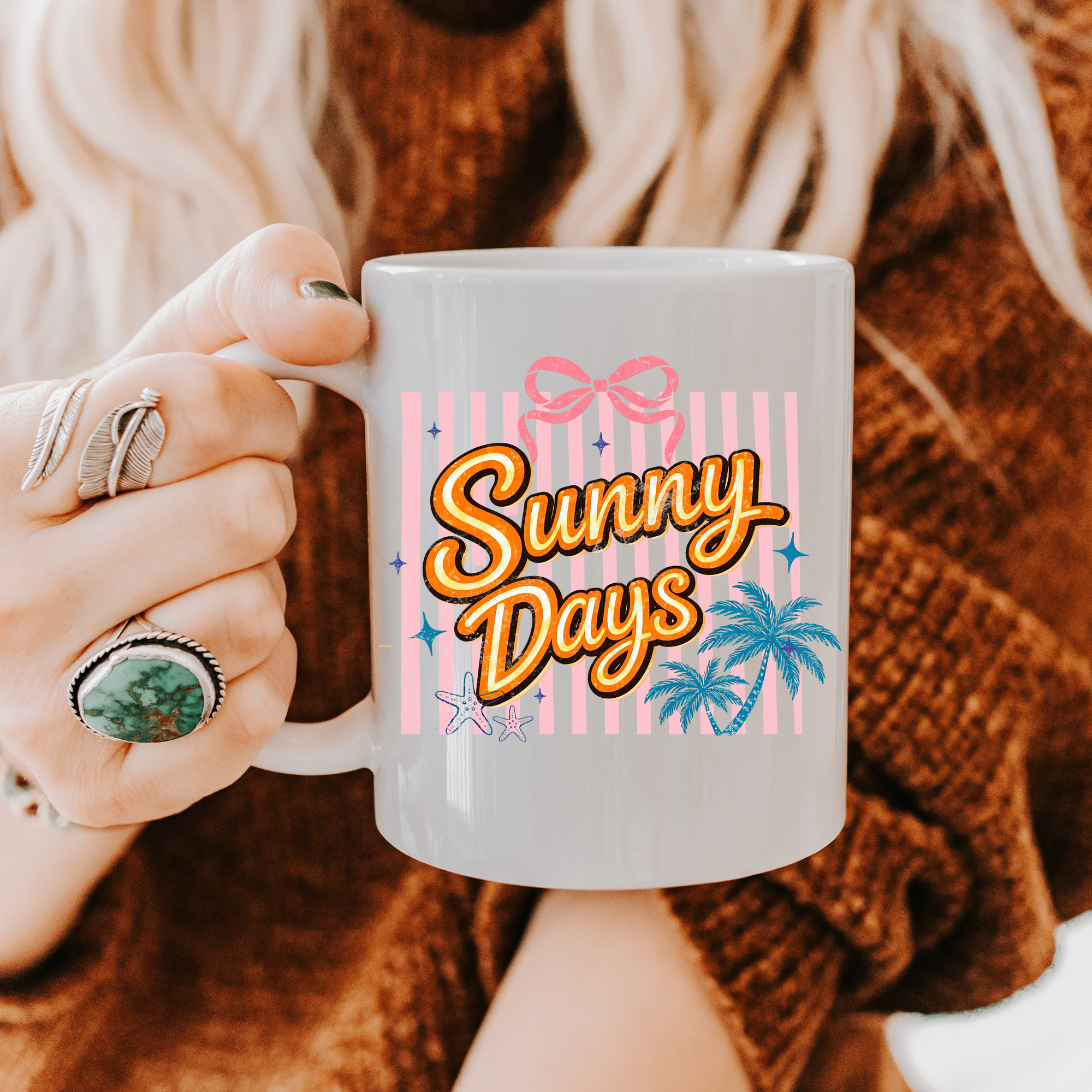 Person holding an 11oz. mug with 'Sunny Days' design, wearing a brown sweater and rings.
