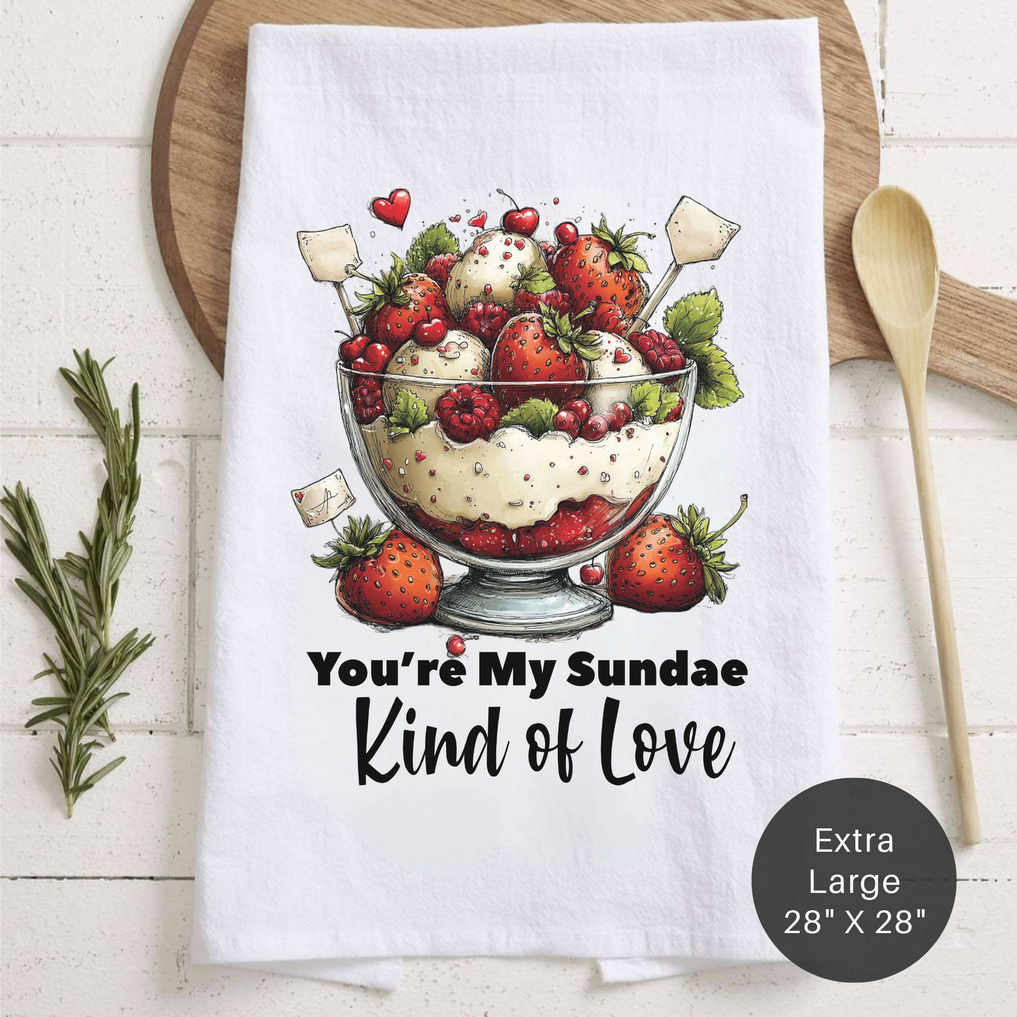 Tea towel with dessert illustration and text ' You're My Sundae Kind of Love on a wooden surface.
