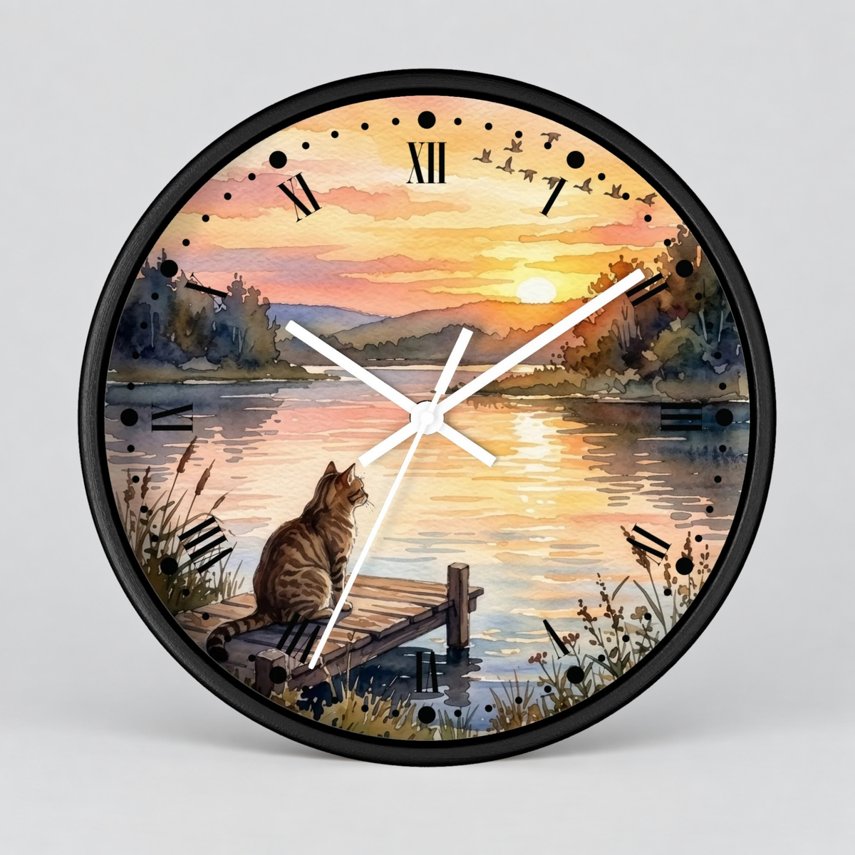 A round wall clock with a black frame and a printed scenic design of a cat sitting on a dock by a lake at sunset. The clock face includes Roman numerals and white hands, shown against a light gray background.
