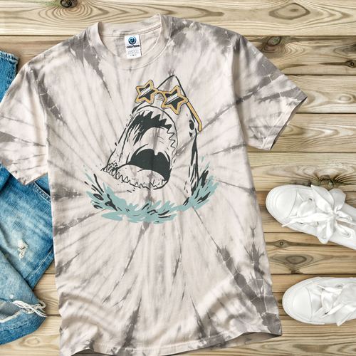 Tie-dye t-shirt in the color Spider Silver with a hand drawn shark graphic on a wooden surface with jeans and sneakers.