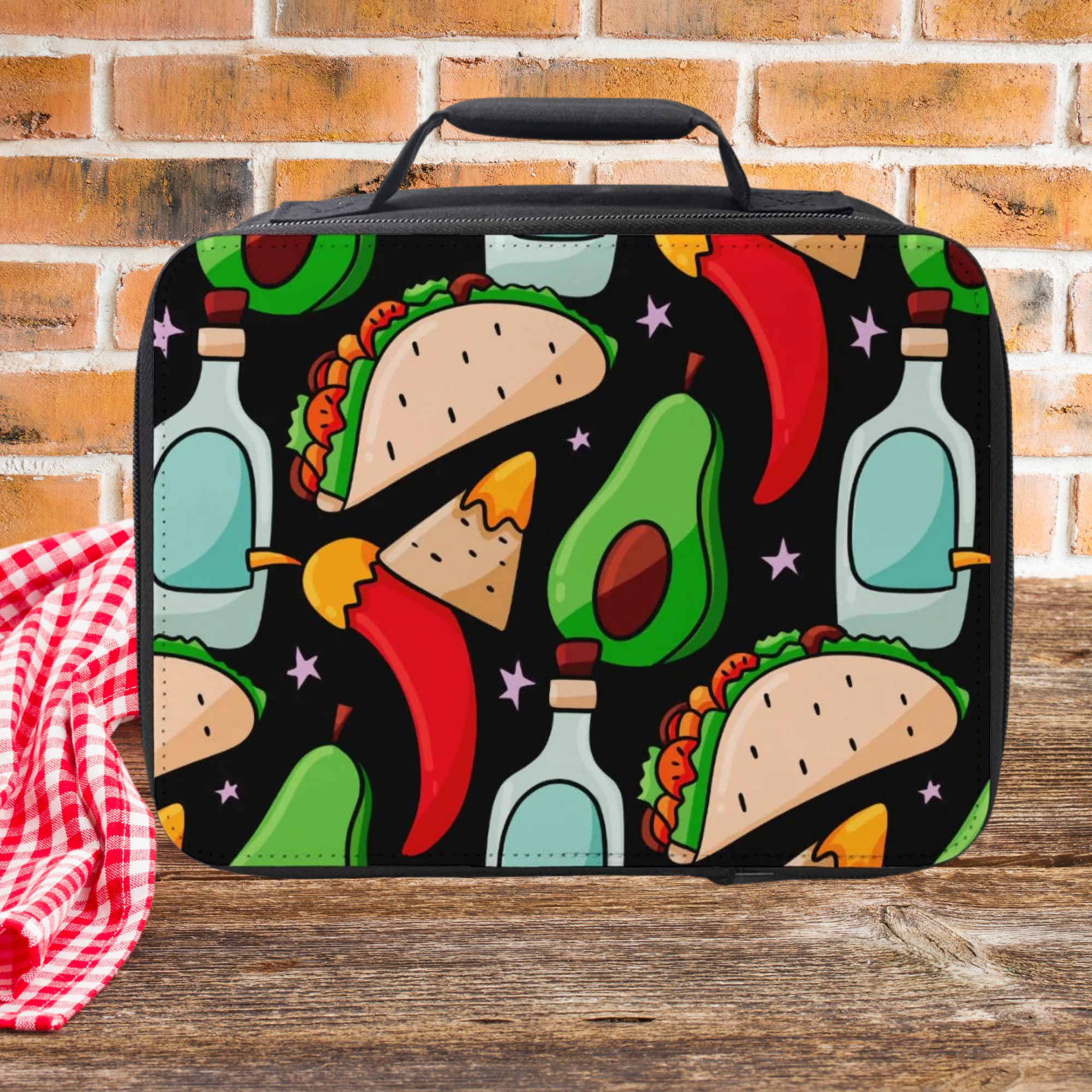  insulated lunch bag with colorful taco and avocado design on a wooden picnic table with a brick wall background