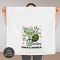 Person holding a decorative towel with a cartoon olive and martini glass design, text 'You're the Olive to my Martini' and names 'Owen & Harper'.