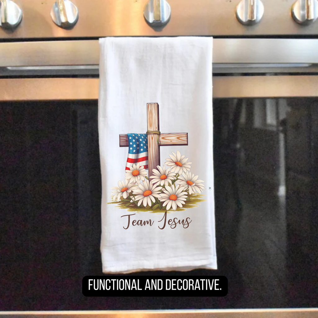 Decorative tea towel with cross, American flag, and flowers hanging on a stove handle.