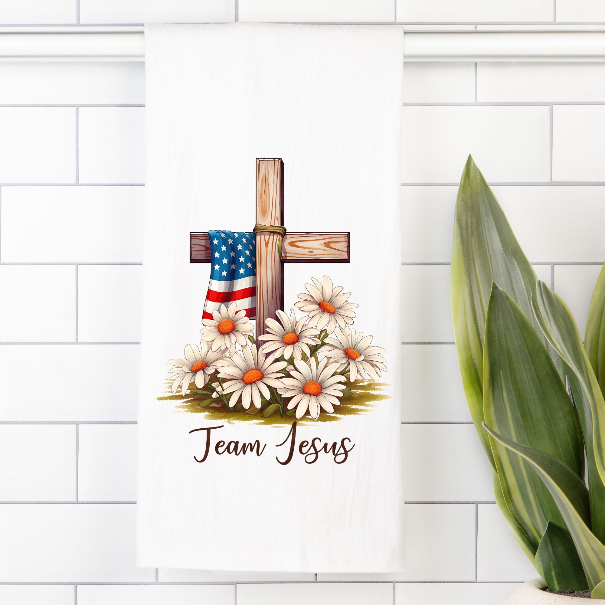 Decorative tea towel with cross, American flag, and flowers on a white tiled wall.