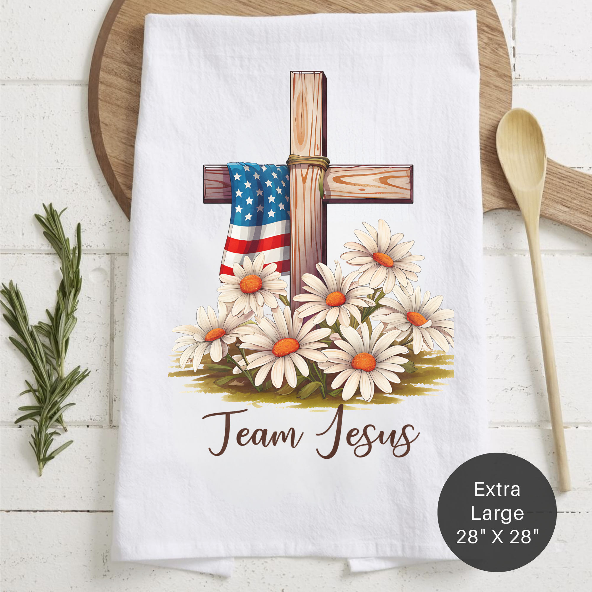 Tea towel with cross, American flag, and daisies design with text 'Team Jesus' on a wooden surface. 