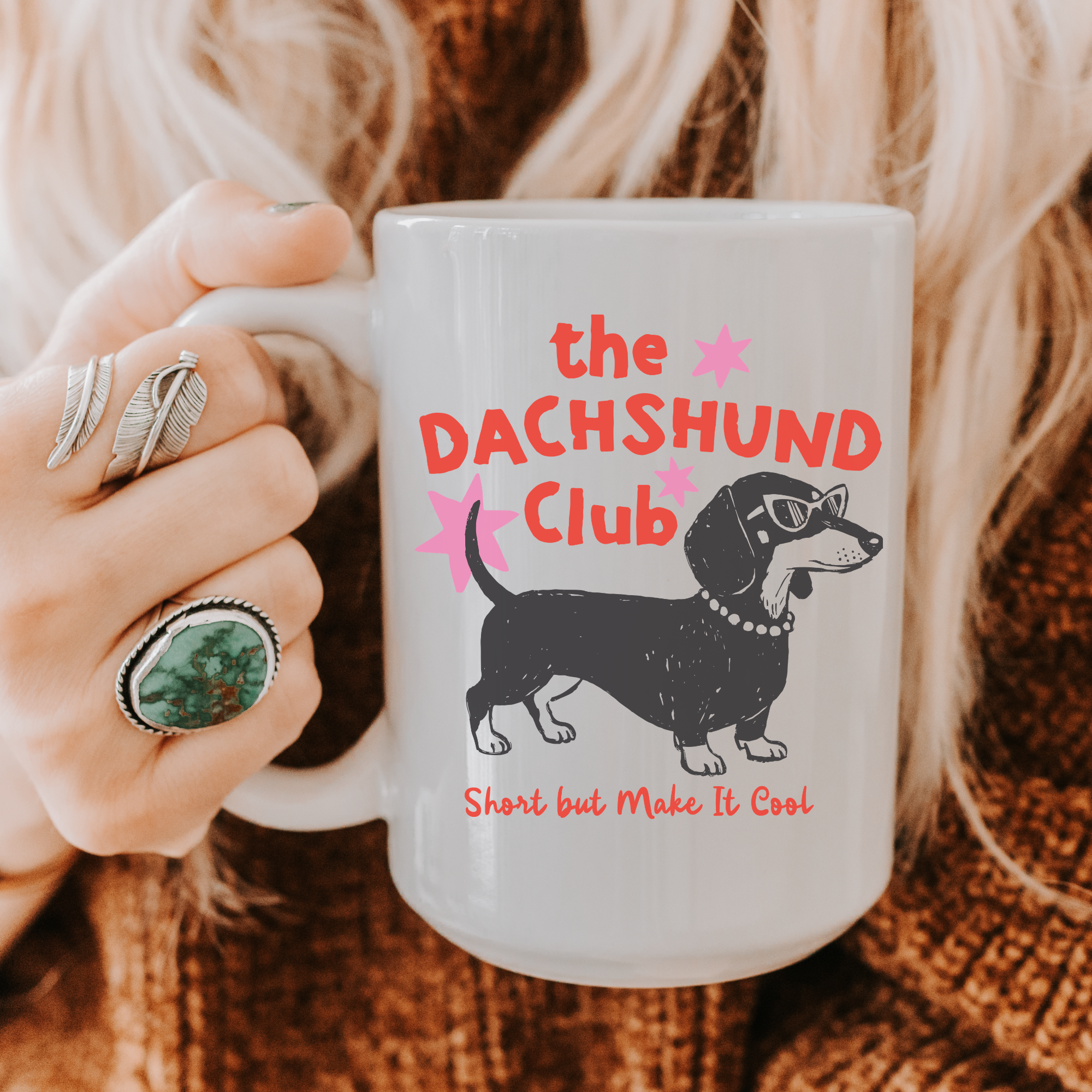 Person holding a mug with 'the DACHSHUND Club' design featuring a dachshund illustration.
