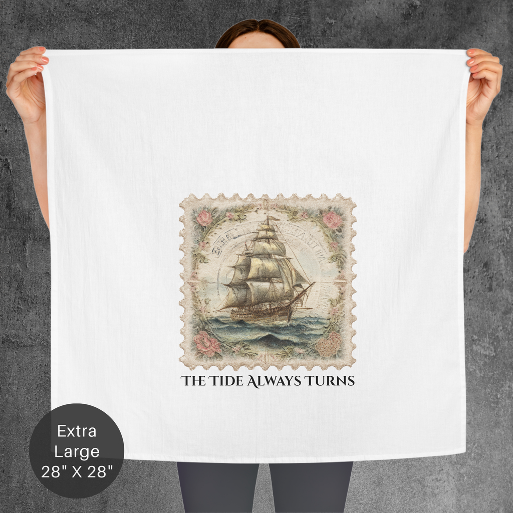 Person holding a large tea towel with a ship design and text 'The Tide Always Turns' on a gray background