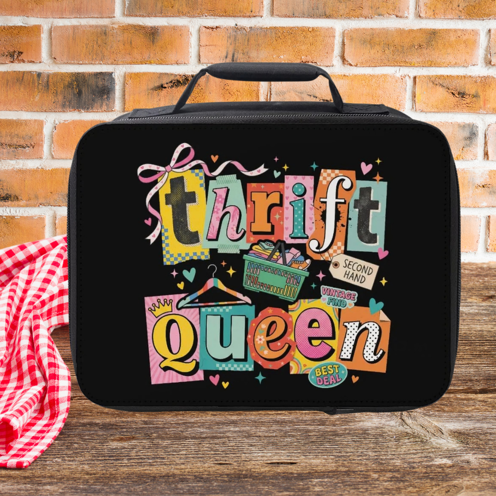 Black lunch bag with colorful 'Thrift Queen' text design on a picnic table against a brick wall background