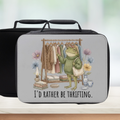 Lunch box with a frog illustration and 'I'd rather be thrifting' text on a blurred background