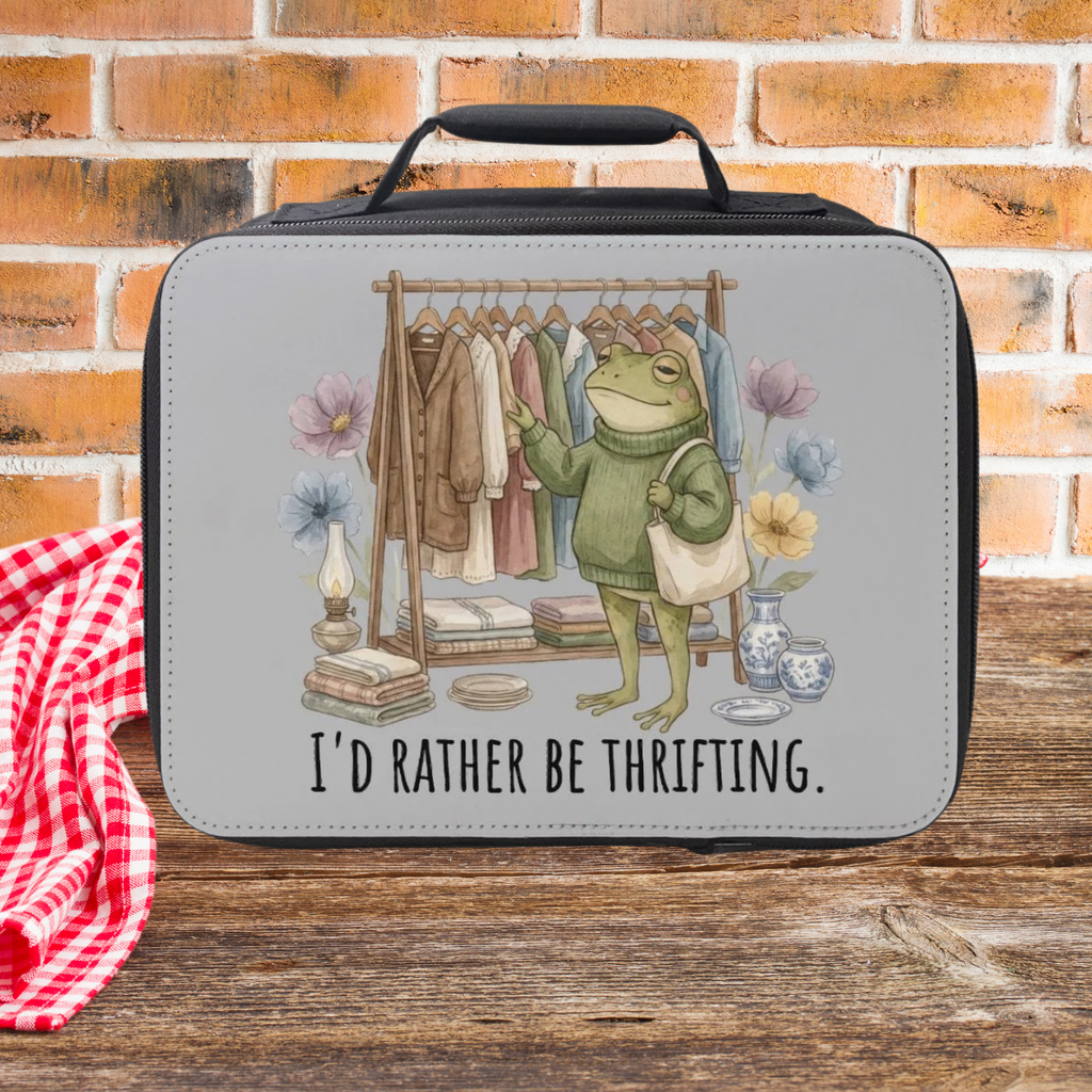 Gray lunch bag with a frog graphic and 'I'd Rather Be Thrifting' text against a brick wall background.