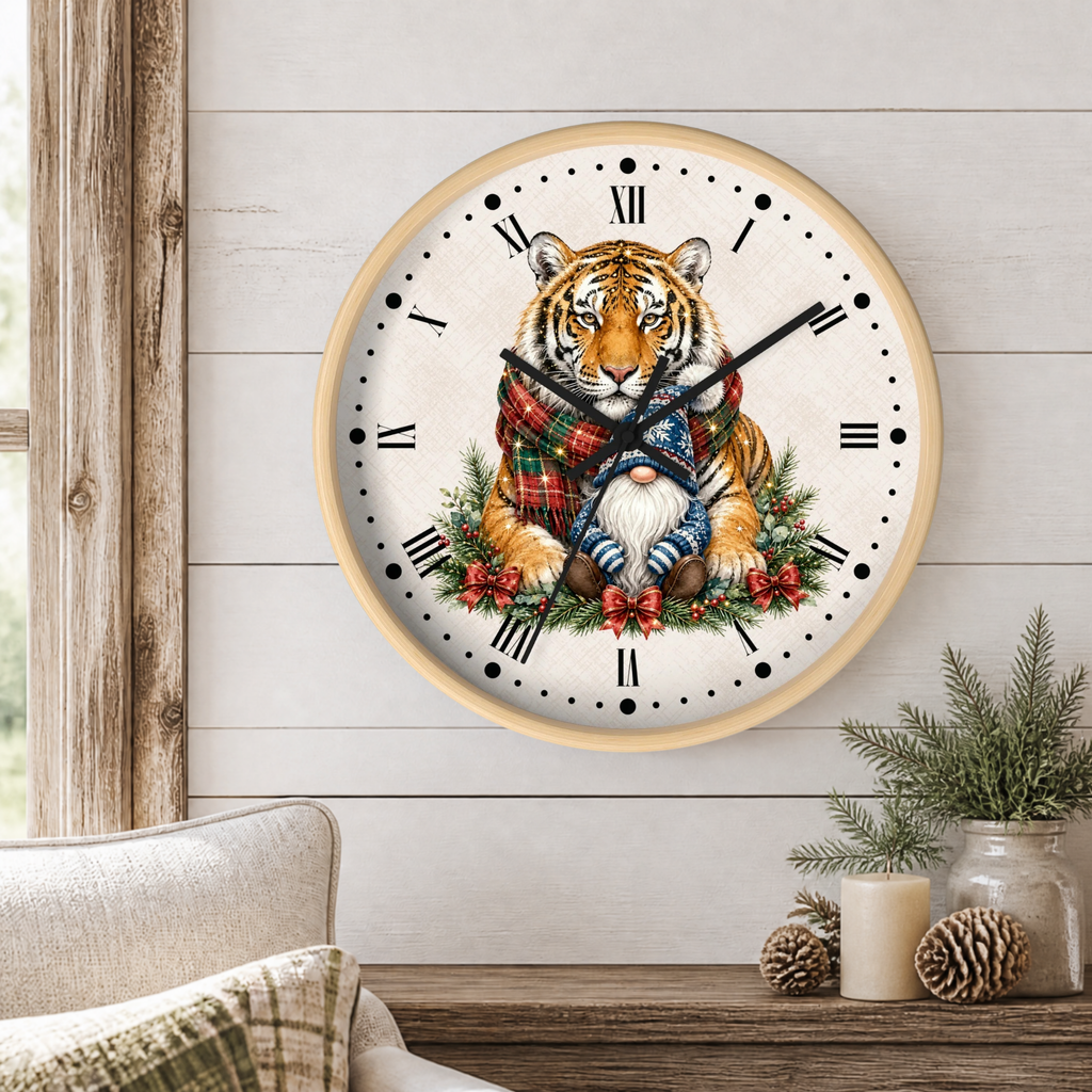 A round wall clock with a light wood frame hangs on a white shiplap wall above a rustic wooden table. The clock face features a detailed illustration of a tiger wearing a red plaid scarf and blue pants, sitting among green pine branches and red berries.
