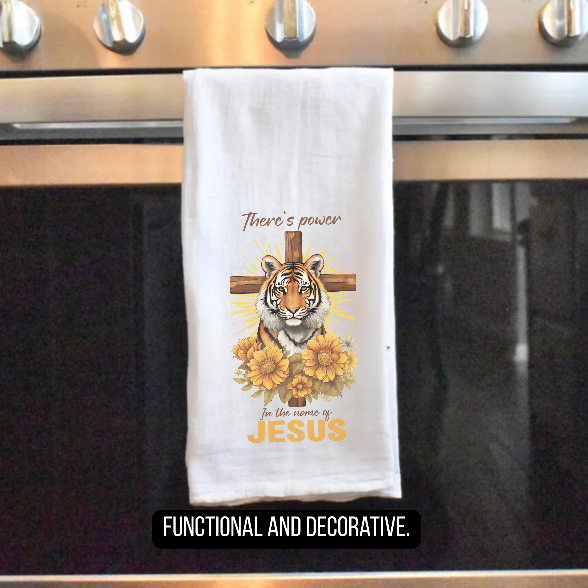 Decorative tea towel with tiger, cross, and sunflowers hanging on a stove handle.