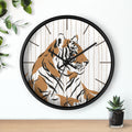 Wall clock with a tiger design on a white wall with a plant and small pot.