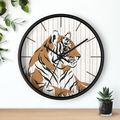 Wall clock with a tiger design on a white wall with a plant and small pot.