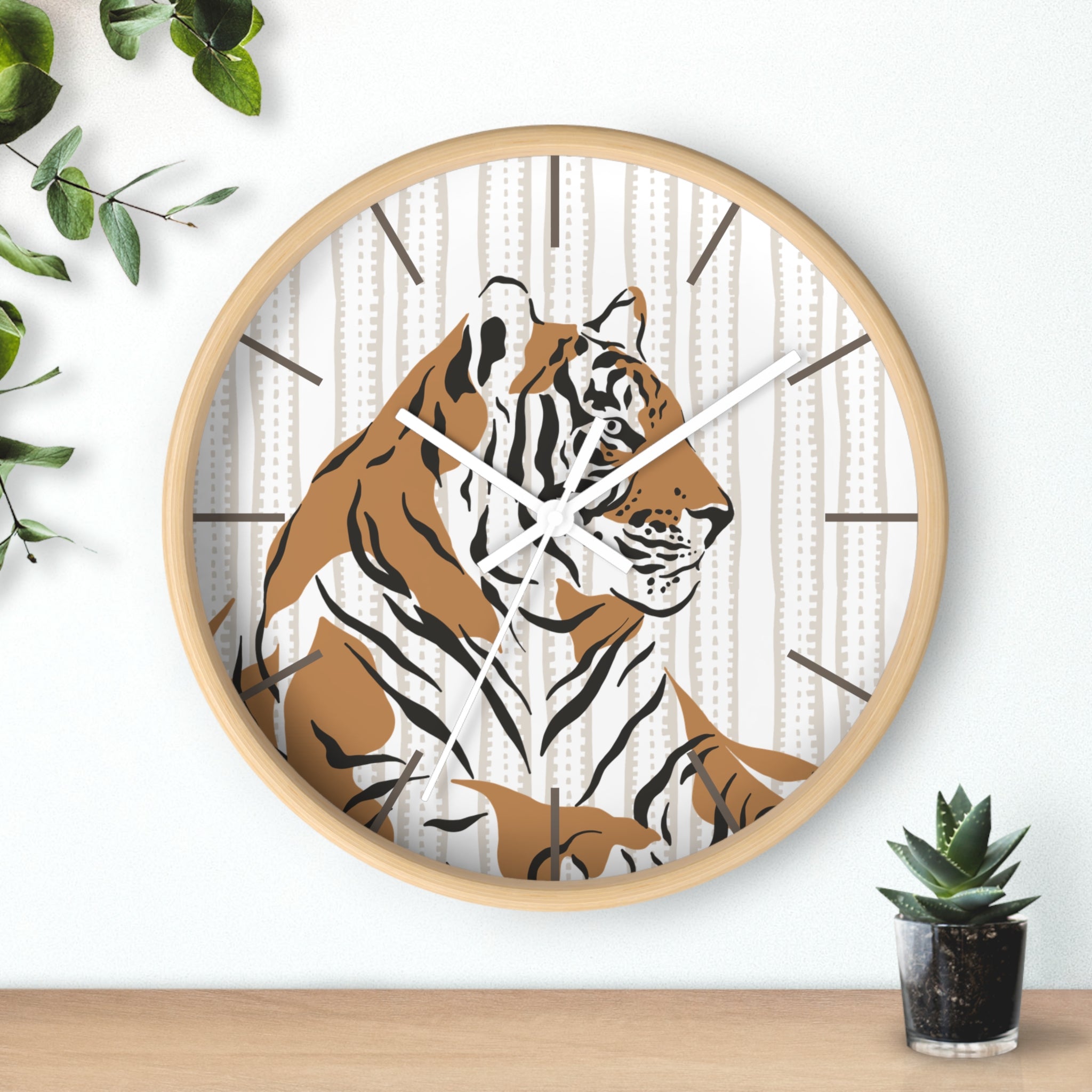 Round wood wall clock with a tiger design on a white wall with greenery