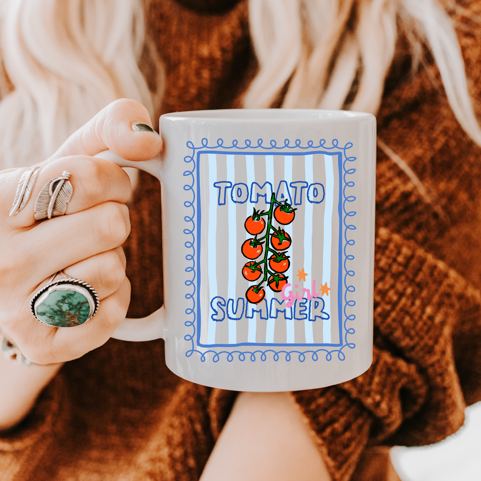 Person holding an 11oz. mug with 'Tomato Summer' design, wearing a brown sweater.
