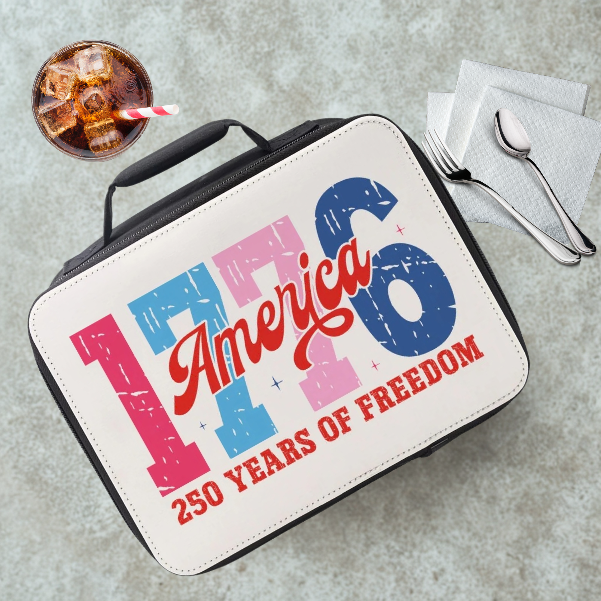 Lunch bag celebrating America's 250 years of freedom on a cafeteria table with a drink and utensils.