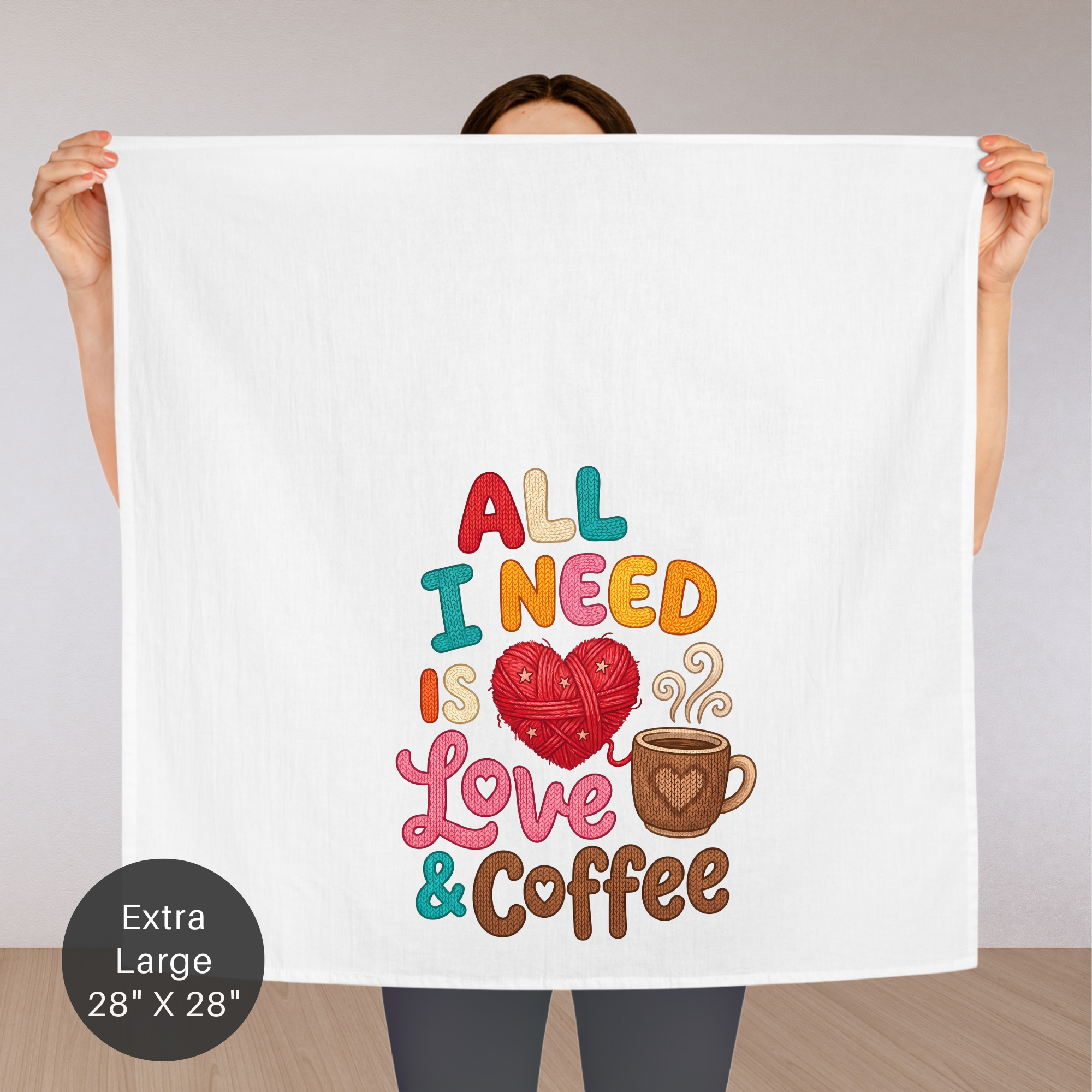 Person holding an extra large tea towel with 'All I need is love & coffee' text and graphics.