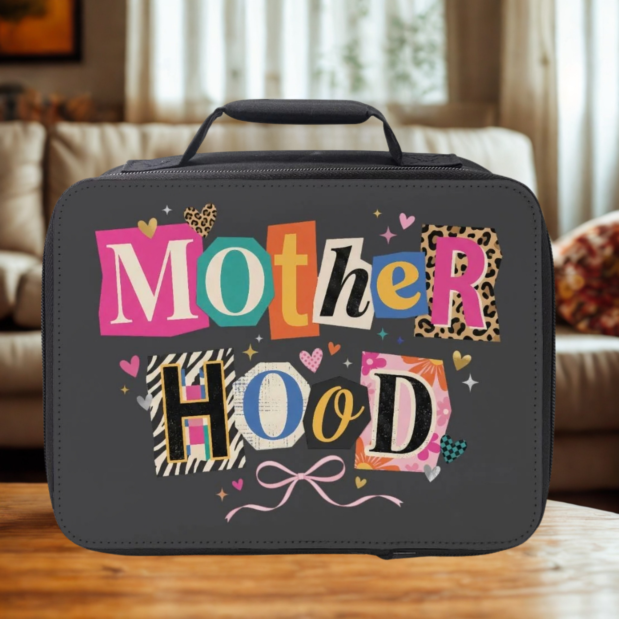 Insulated lunch bag with colorful 'Mother Hood' text on a wooden table in a living room.