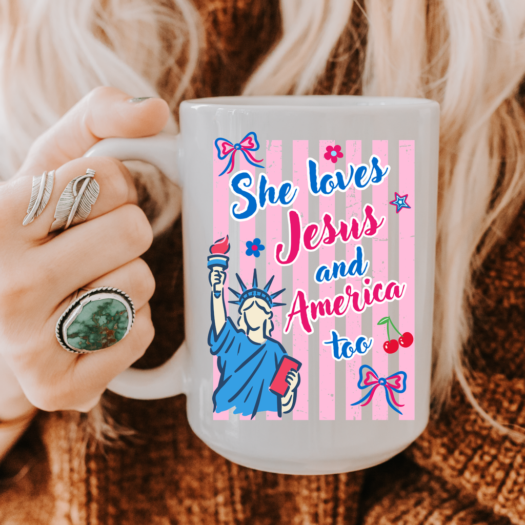 Person holding a 15oz. mug with 'She loves Jesus and America too' design