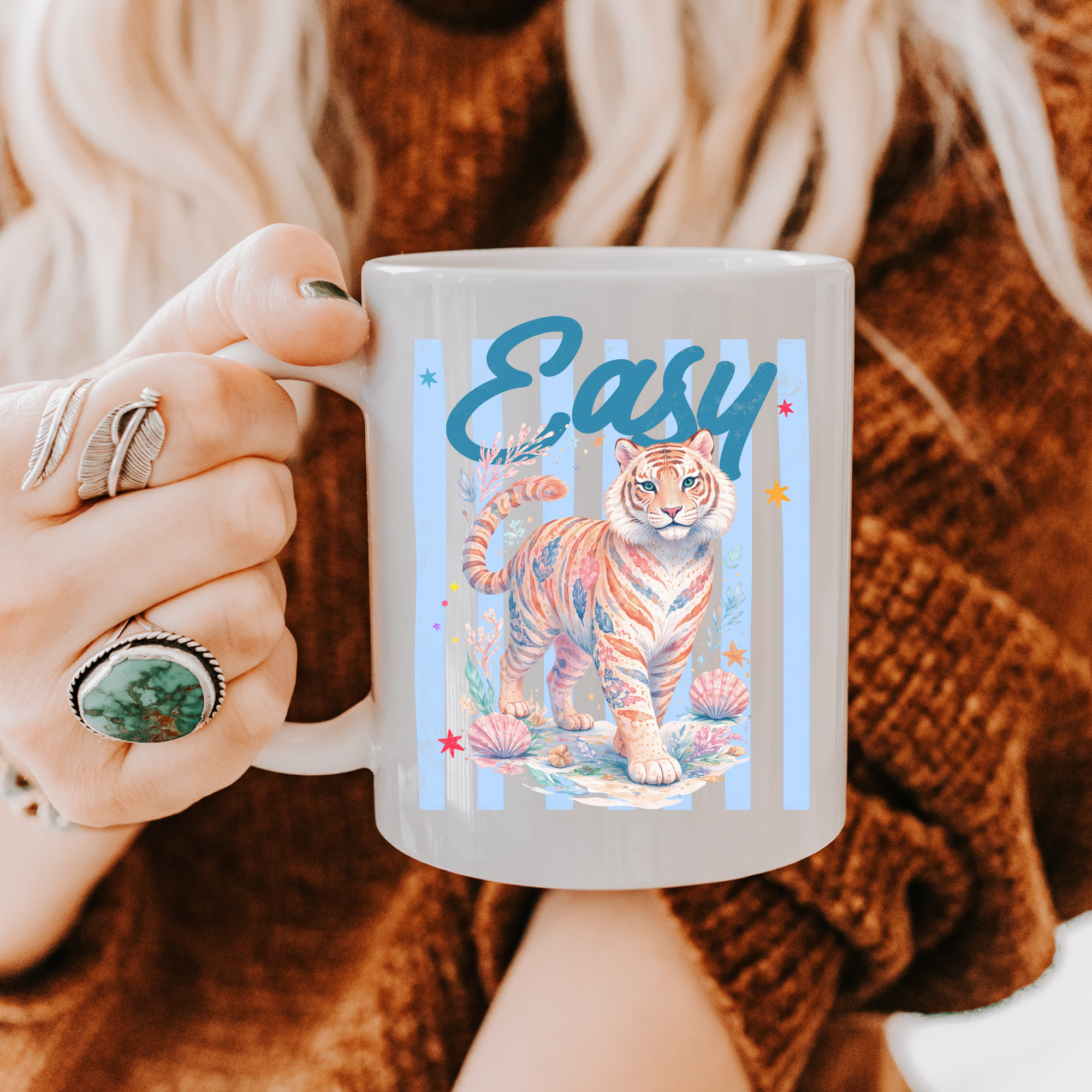 Person holding an 11oz. mug with a tiger design and 'Easy' text, wearing a brown sweater.