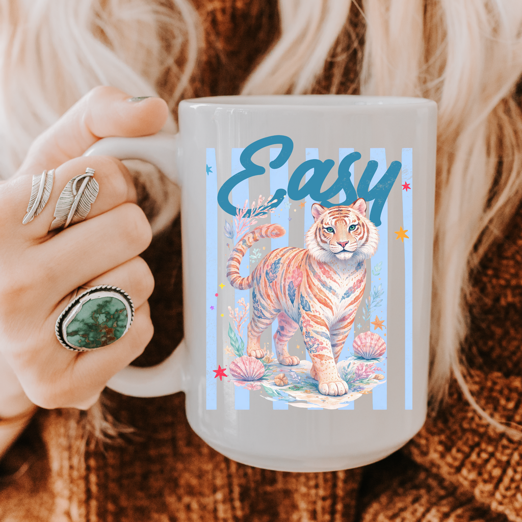 Person holding a 15oz mug with a tiger design and 'Easy' text