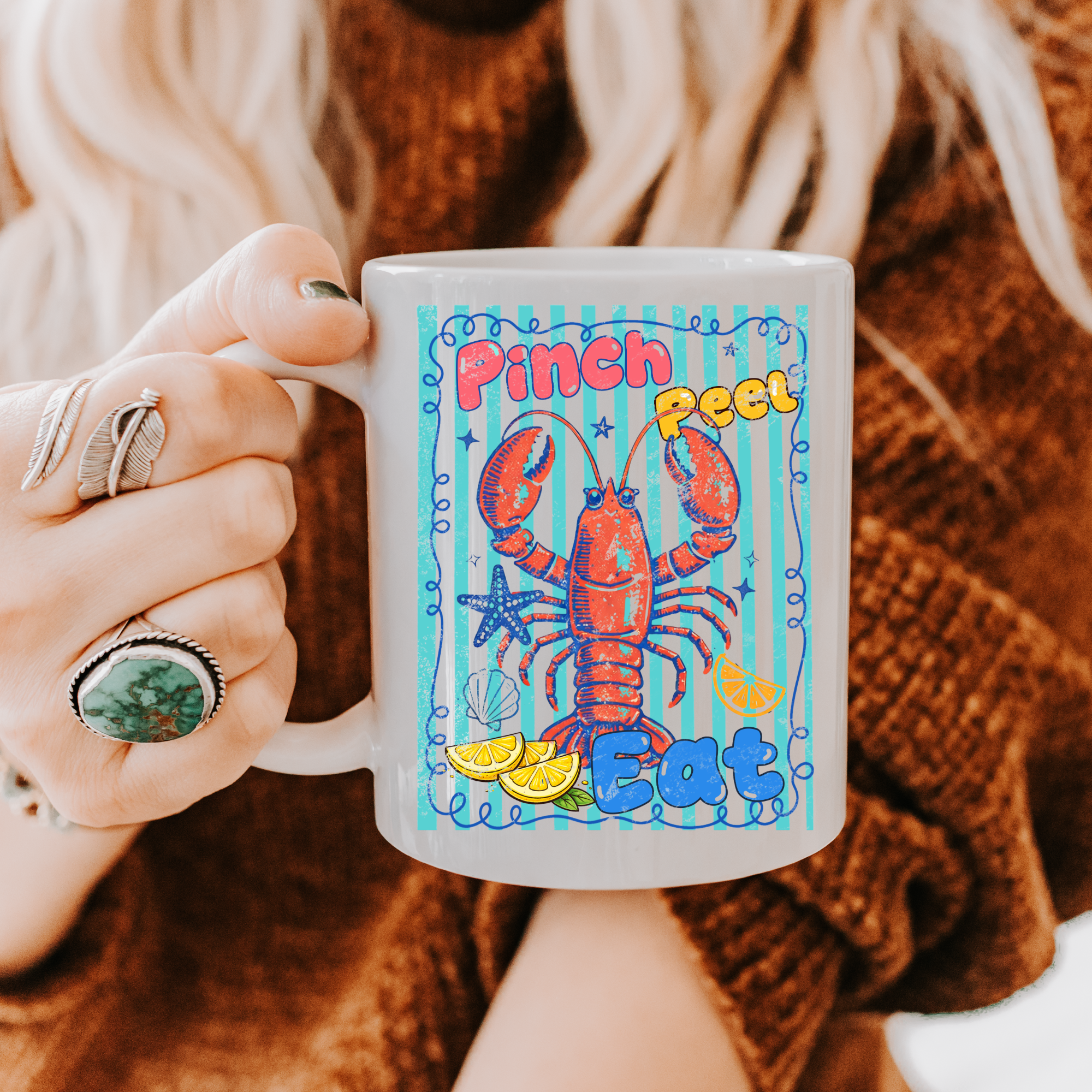 Person holding an 11oz. mug with a colorful lobster design and text.