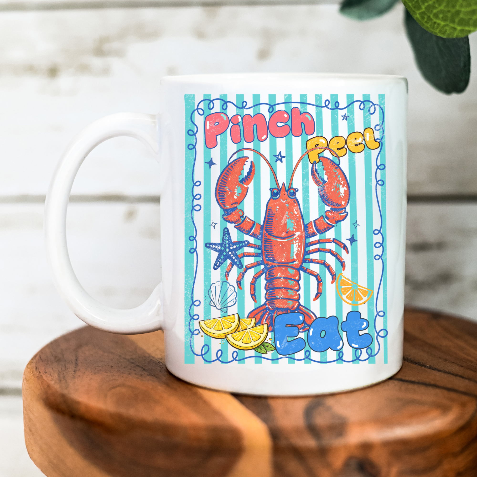 White 11oz. mug with a colorful lobster design and text on a wooden surface.