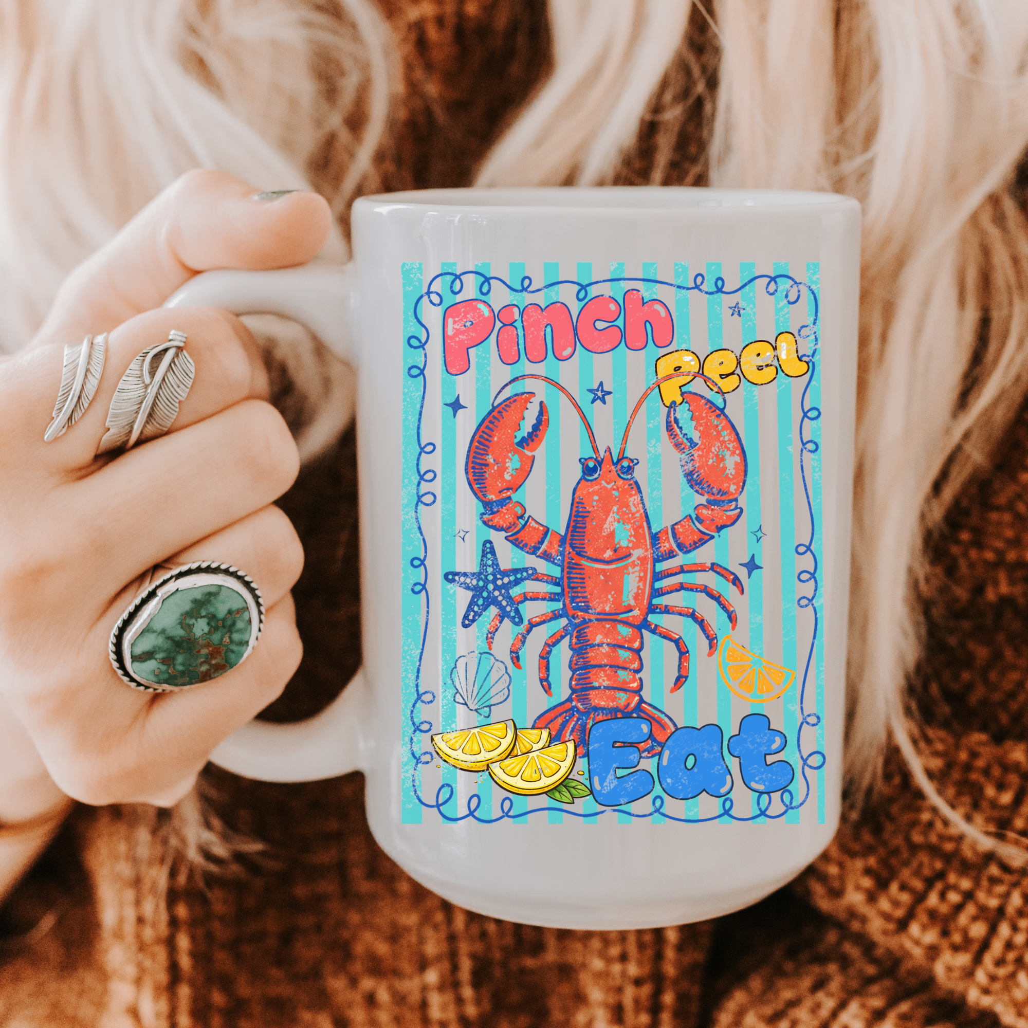 15oz. Mug with a colorful lobster design and text held by a person wearing rings.