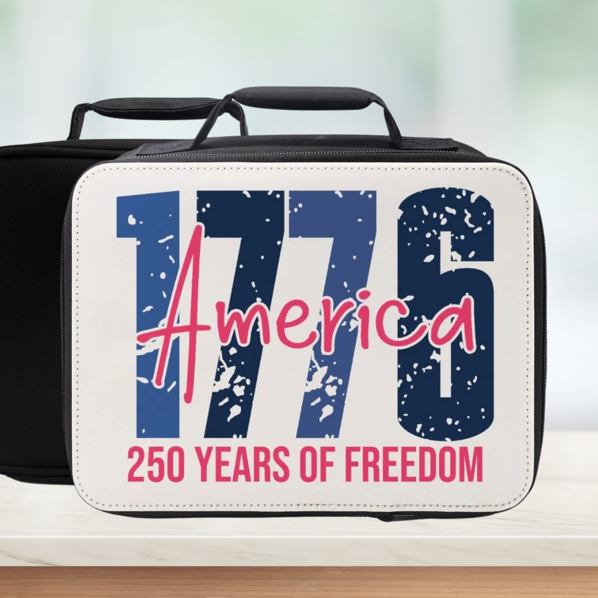 Black and white lunch box with '1776 America 250 Years of Freedom' text on a blurred background