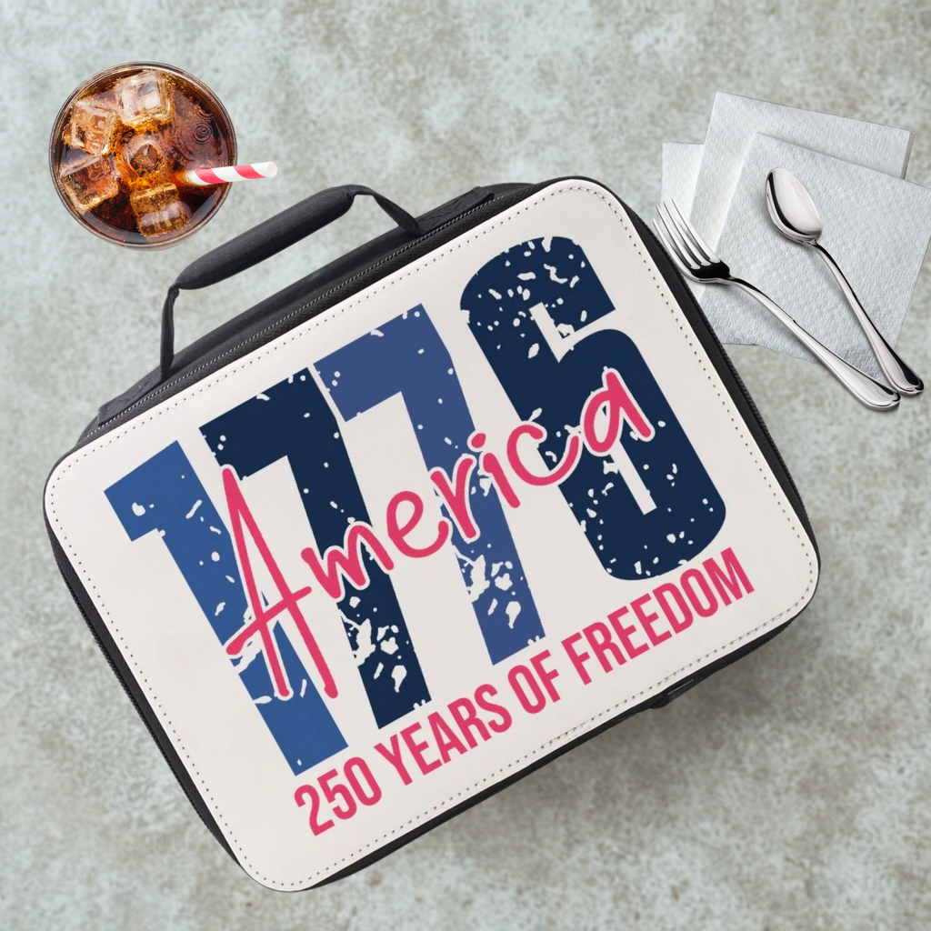 Lunch box with 'America 250 Years of Freedom' text on a gray table with a drink and utensils.