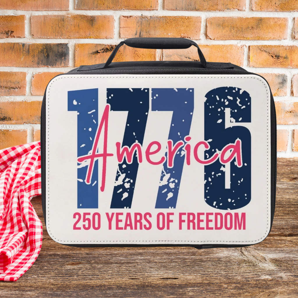 Lunch bag with '1776 America 250 Years of Freedom' text on a picnic table  against a brick wall background