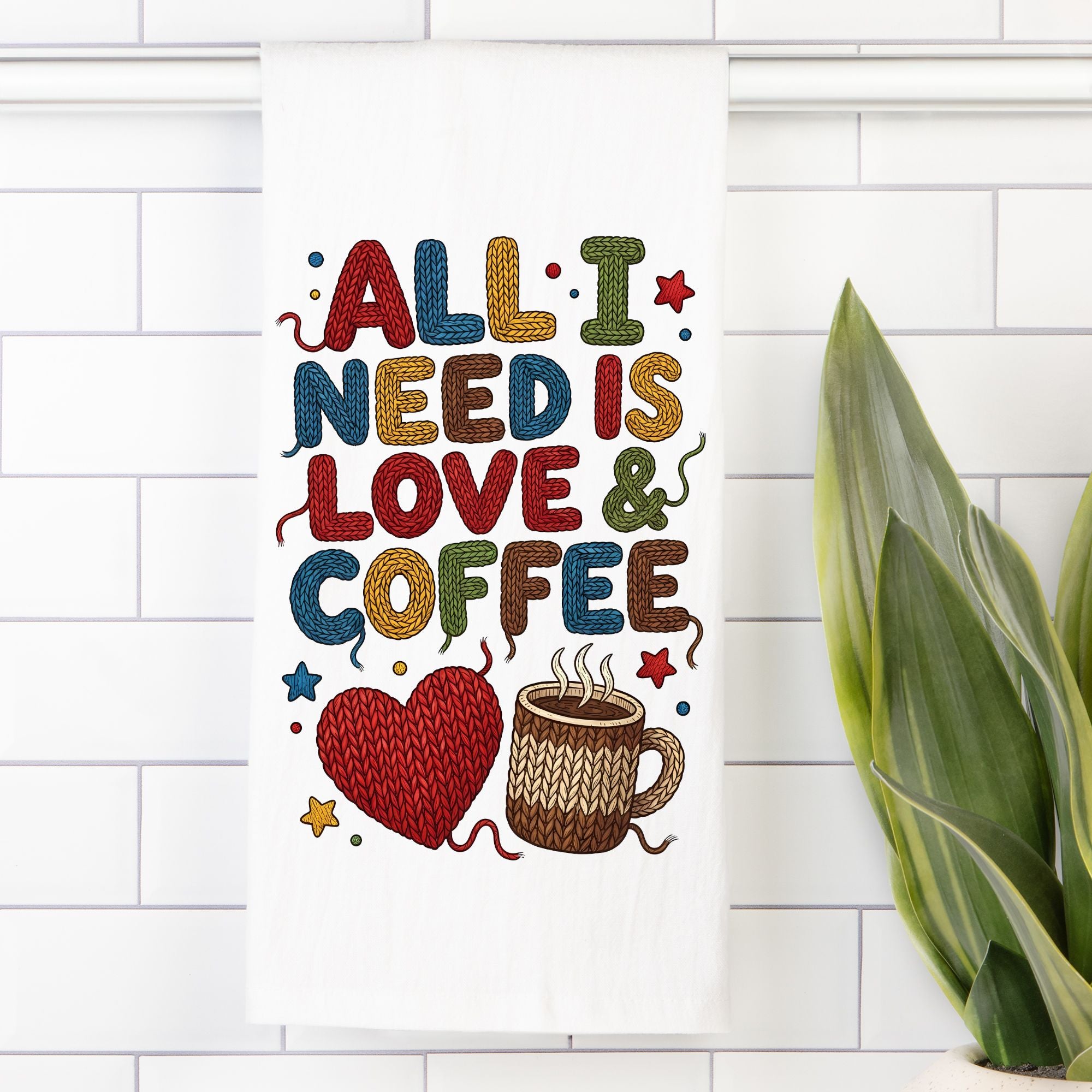 Decorative tea towel with 'All I Need is Love & Coffee' text on a white tiled wall.
