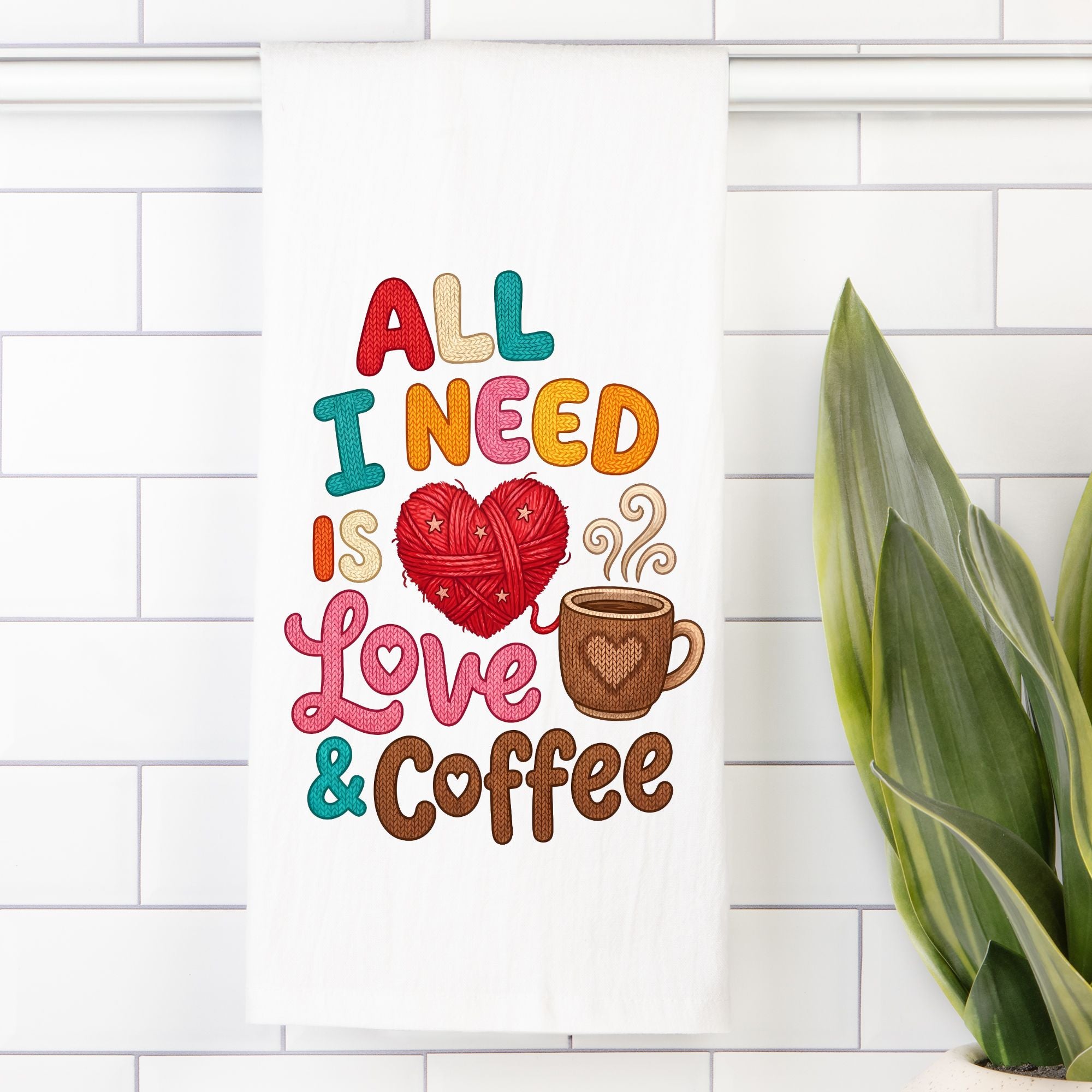 Tea Towel with Colorful text 'All I Need is Love & Coffee' with a heart and coffee cup design on a white tiled wall.