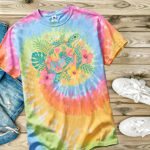 Tie-dye t-shirt with a sea turtle and floral design on a wooden surface with jeans and shoes.