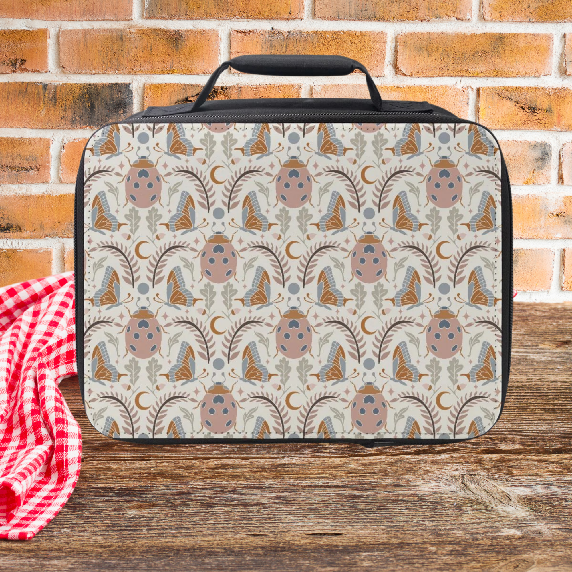 Boho Butterfly Beetle Patterned lunch bag on a wooden picnic table with a brick wall background