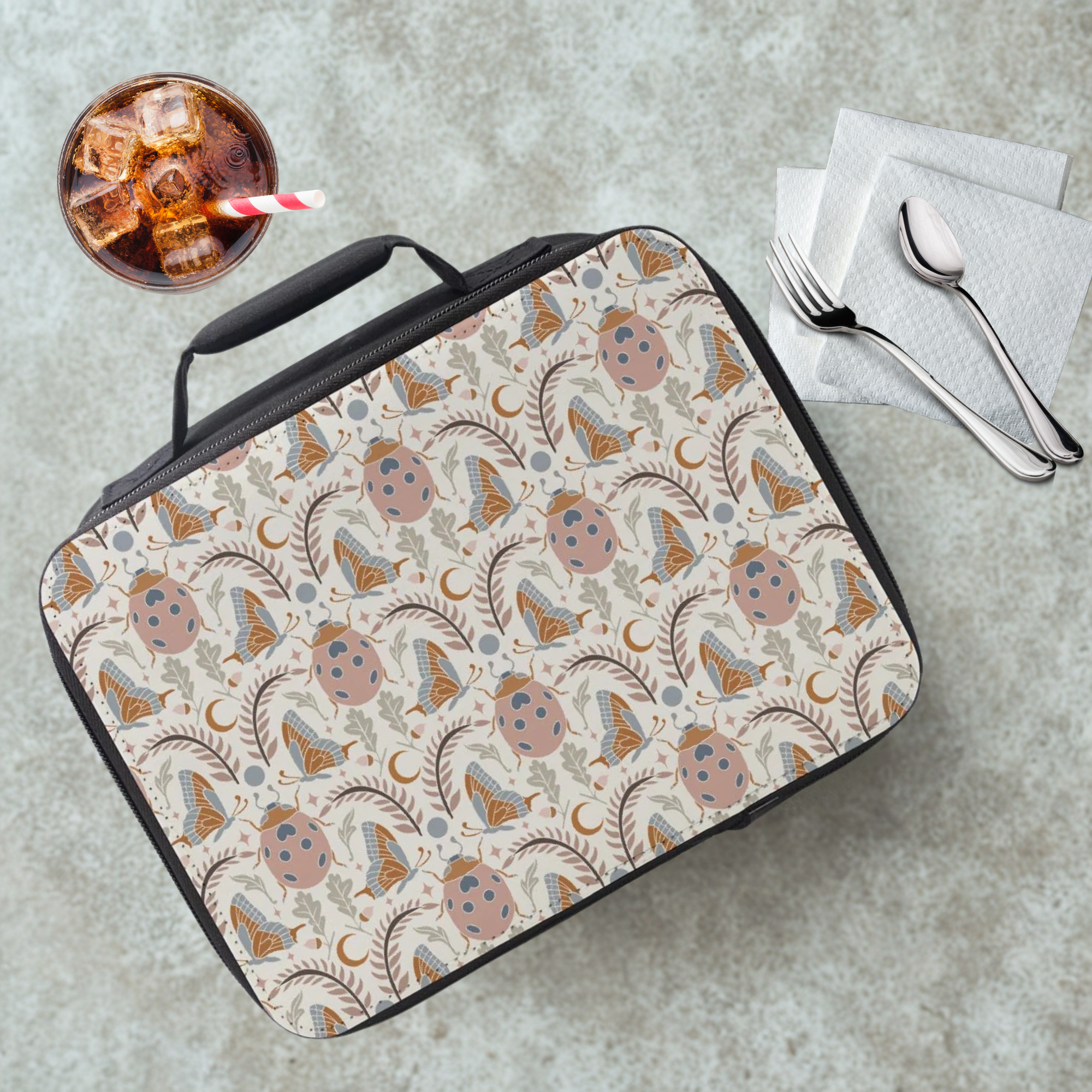 Insect patterned lunch bag on a cafeteria table with a drink and utensils in the background