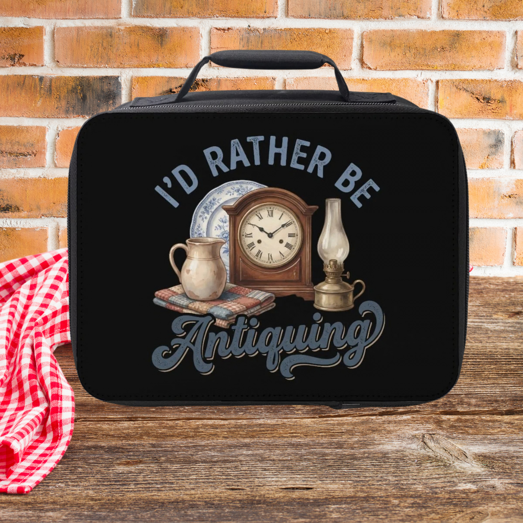 Black lunch bag with 'I'd Rather Be Antiquing' design featuring a clock, lamp, and pitcher on a brick wall background.
