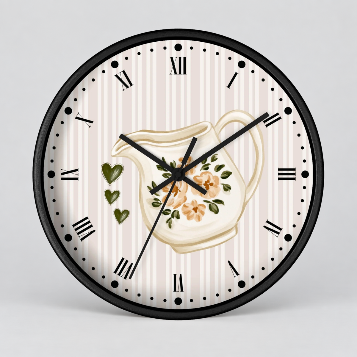 Round wall clock with a black frame, Roman numeral hour markers, and a cream clock face featuring a floral cream pitcher illustration and three green hearts, shown on a light gray background.