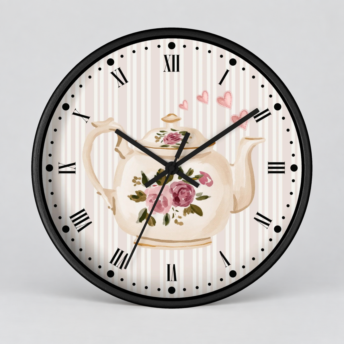 Round wall clock with a black frame and a tea-themed face featuring a cream teapot with pink roses, Roman numerals, and a light striped background.