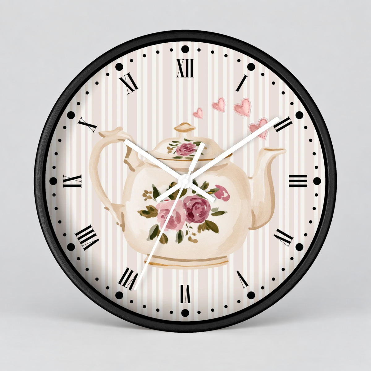 Round wall clock with a black frame, Roman numerals, and a vintage-style floral teapot illustration on a cream and pink striped face, shown against a light gray background.