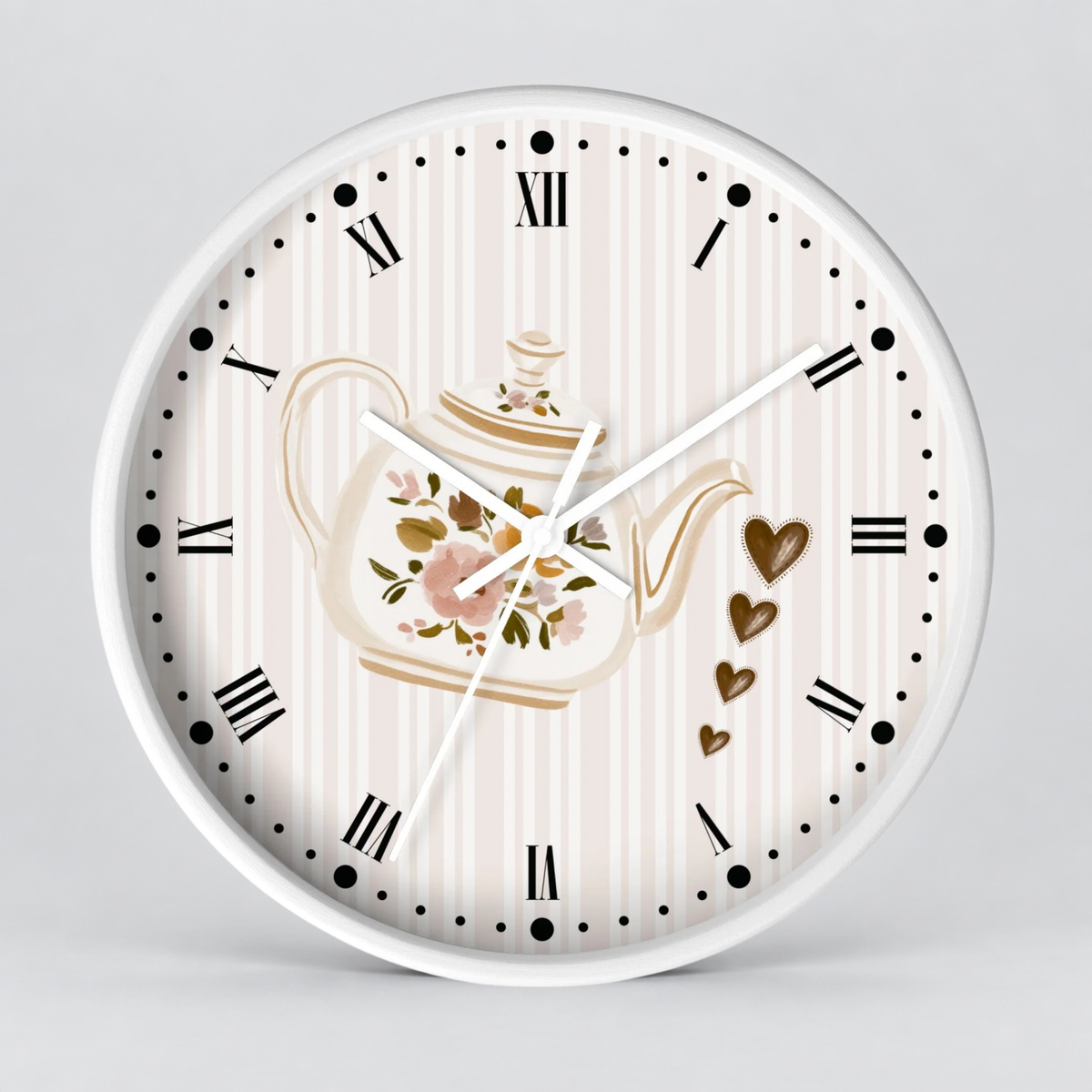 Round wall clock with a white frame and a cream-and-white striped dial. The face features a central floral teapot illustration, black Roman numerals, black dot hour markers, white hands, and three dangling gold heart charms on the right side.